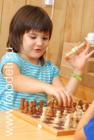 Ребенок держит шахматные фигуры в руке, на фото дети занимаются спортом