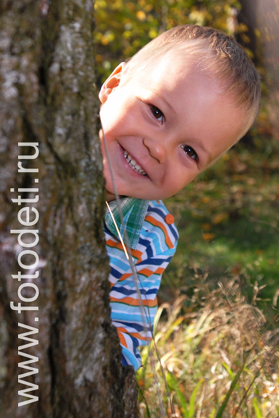 Фото детей в игре: Мальчик прячется за деревом.