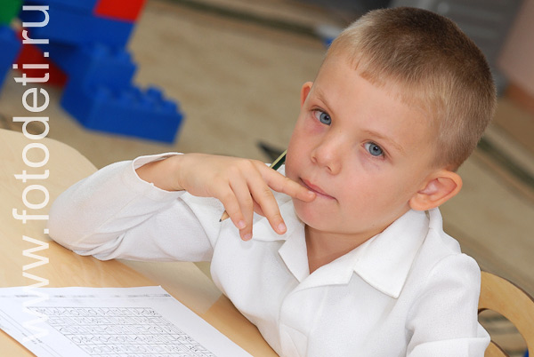 На фото дети учатся. Задумчивый мальчик с голубыми глазами.