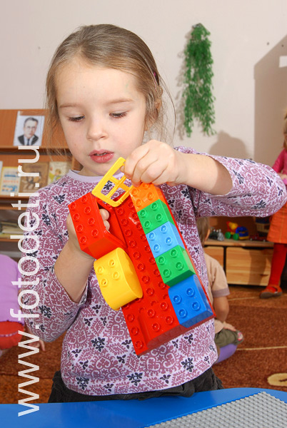 Фото детей в игре: Фотография девочки, играющей в конструктор лего.