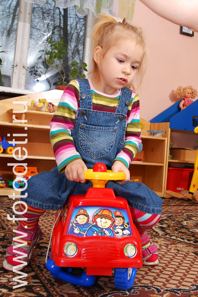 Фото детей в игре: Девочка катается на машинке.
