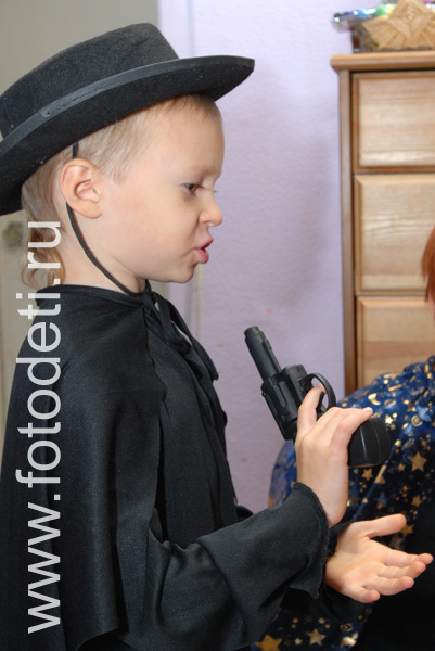 Фото детей на праздниках. Мальчик в шляпе и с пистолетом в руках.