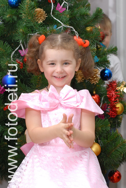 Дети на фото детского фотографа: Фотография весёлой девочки на фоне новогодней ёлочки.