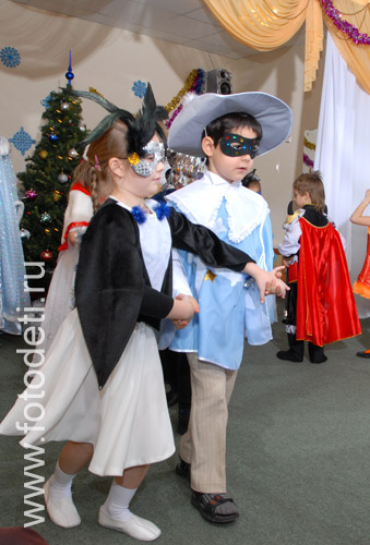 Фотогалерея детских праздников. Мальчик с девочкой в карнавальных костюмах танцуют на празднике.