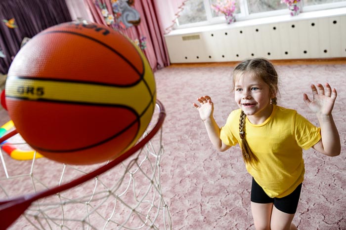 Ребенок бросает баскетбольшый мяч в кольцо