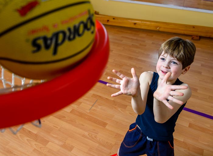 Девочка бросает мяч на занятиях физкультурой в детском саду