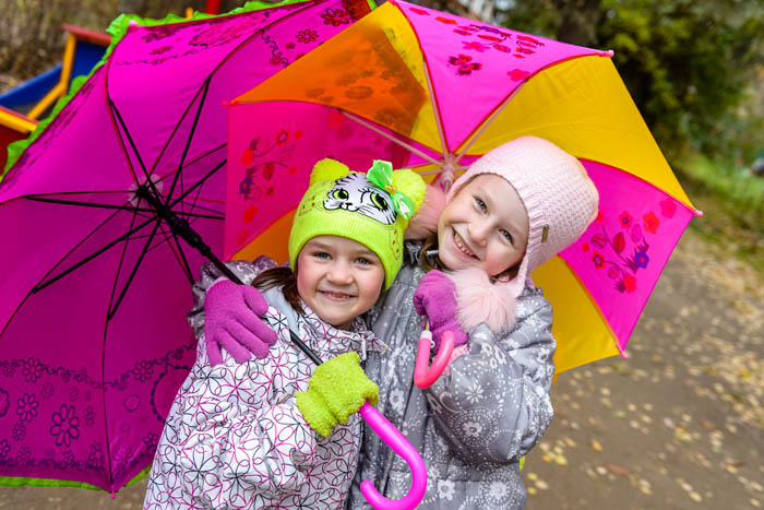 Дети с зонтиками осенью на детской площадке