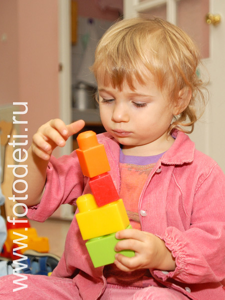 Фото детей в игре: Девочка играет в кубики.