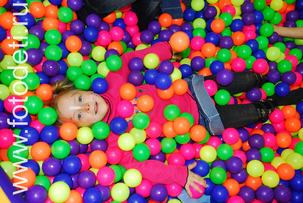 Фотографии детей из архива детского фотографа. Девочка лежит в море цветных шариков.