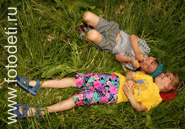 Фотографии детей в авторском фотобанке. Мальчик с девочкой лежат на траве и радуются жизни.