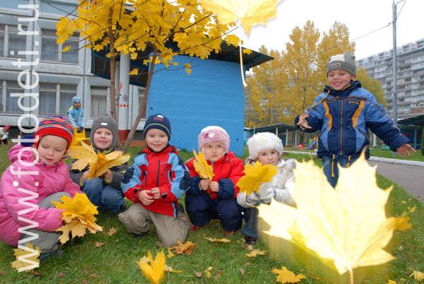 Фотографии детей из архива детского фотографа. Дети играют с осенними листьями на детской площадке.