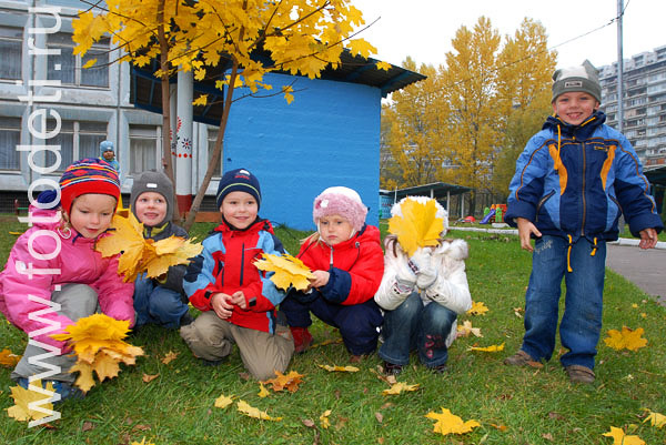 Фотографии детей из архива детского фотографа. Фото играющих с осенними листьями детей на детской площадке.
