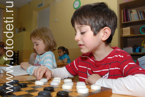 Фотографии здоровых детей. Обучение детей игре в шашки.