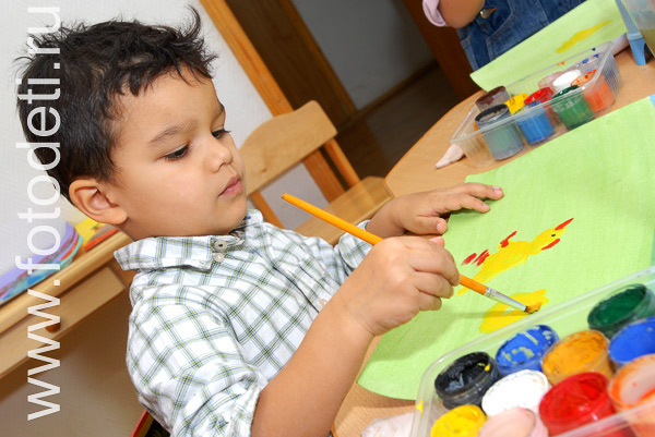 Творческое развитие детей. Мальчик в детском саду рисует красками.