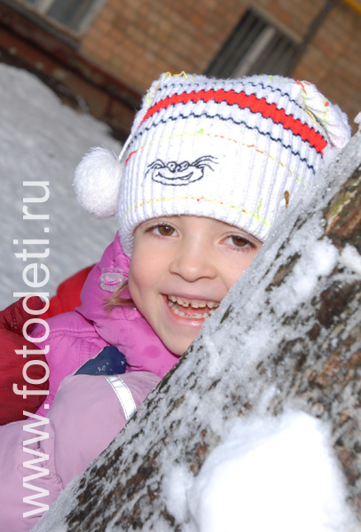 Фотографии детей из архива детского фотографа. Девочка прячется за зимним деревом.
