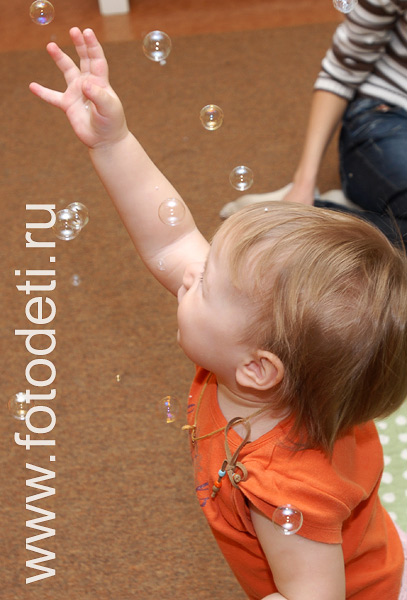 Фото детей в игре: Малыш играет с мыльными пузырями на развивающих занятиях в детском центре.