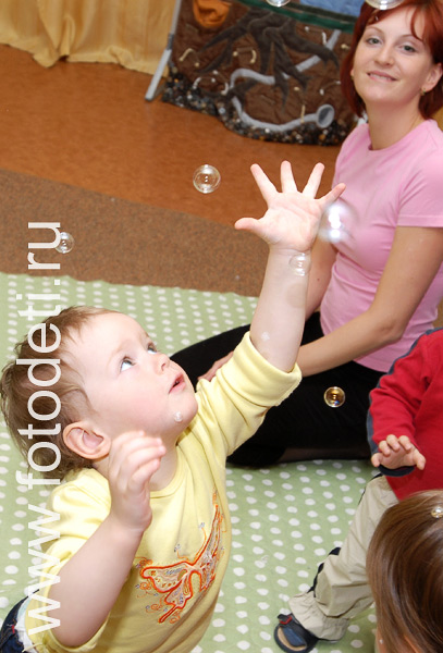 Фото детей в игре: Ребёнок играет с мыльными пузырями на развивающих занятиях в детском центре.
