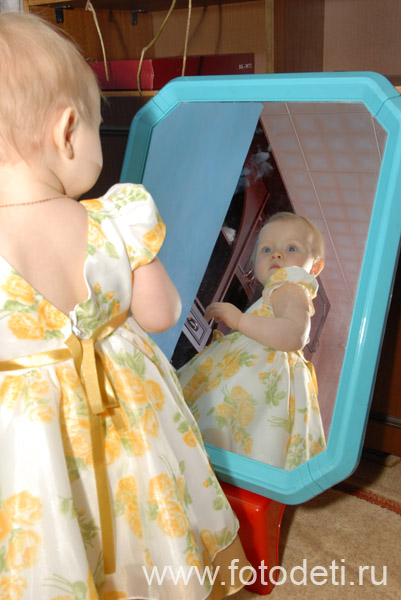 Общение детей. Маленькая девочка в платьице любуется своим отражением в зеркале.