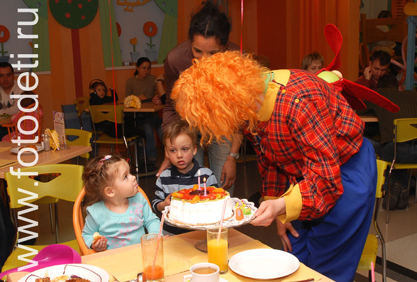 Весёлые детские праздники. Клоун приносит тортик на детском дне рождения.