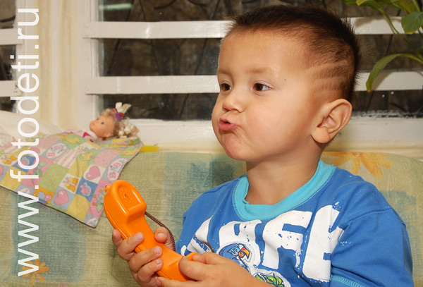 Фото детей в игре: Ребёнок звонит по игрушечному телефону.