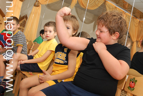Детский фитнес. Здоровый мальчик демонстрирует свои мышцы.