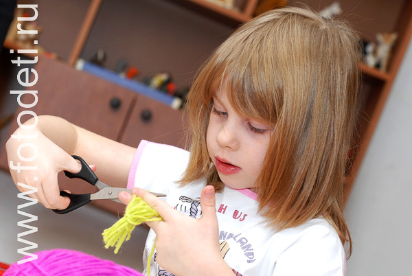 Детские творческие студии. Девочка режет ножницами нитки.