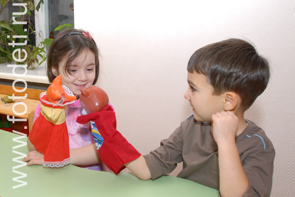 Фото детей в игре: Мальчик с девочкой показывают представление с куклами-перчатками.