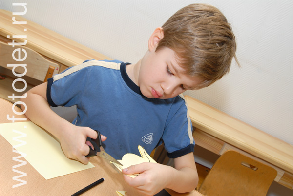 Творческое развитие ребёнка. Мальчик аккуратно режет ножницами бумагу.