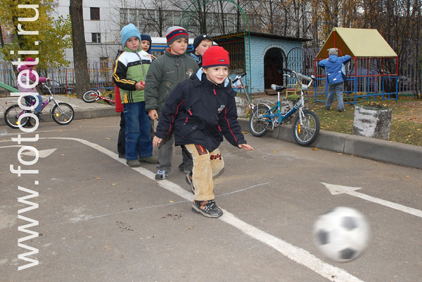 Фото детей в игре: Дети играют в футбол на детской площадке.