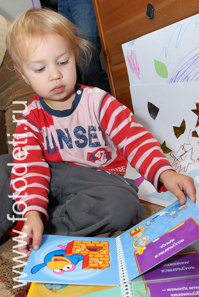 Фотографии детской игры: На фото малыш читает книжку про смешариков.
