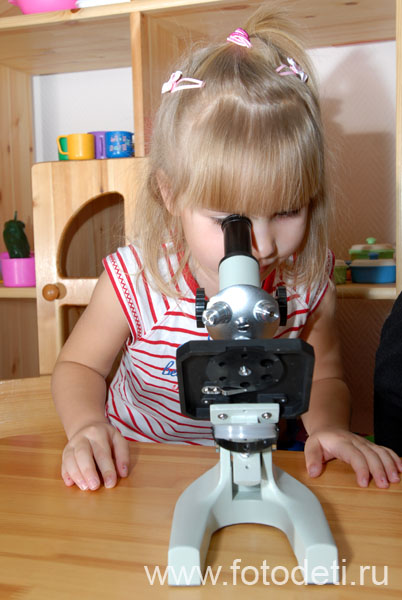 Фотографии детей из архива детского фотографа. Маленькая девочка с интересом знакомиться с микроскопом.