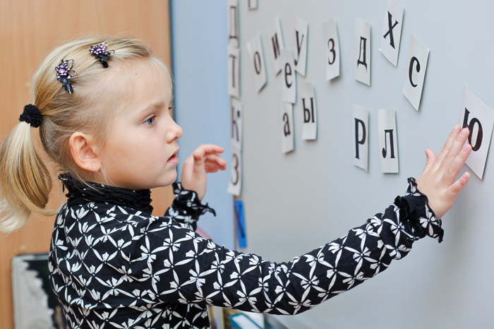 Фото Игоря Губарева: Девочка у доски с серьёзным видом складывает слова из букв.