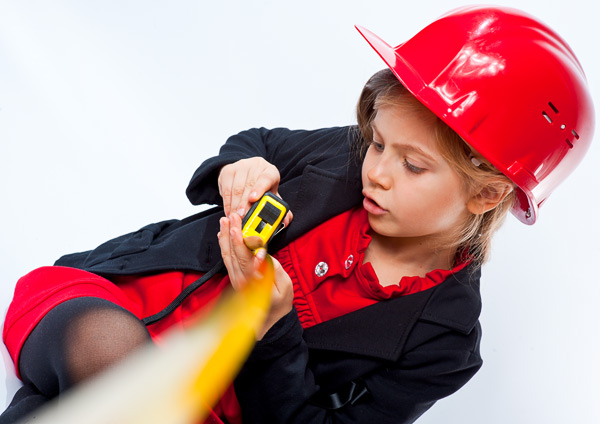 Девочка в строительной каске с интересом что-то измеряет строительной рулеткой. Фотография, ID 17218