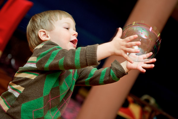 Мальчик увлечён игрой с прозрачным шариком.