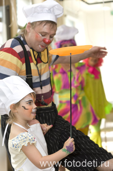 Фотографии детей из архива детского фотографа. Клоун на детском празднике учит детей показывать цирковые номера.