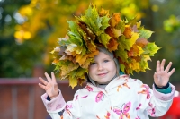 Венок из осенних листьев на голове девочки в детском саду
