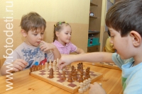 Мальчики играют в шахматы Мальчишки разыгрывают партию в шахматы, на фото дети занимаются спортом
