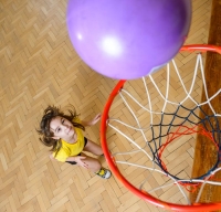 Девочка забрасывает мяч в баскетбольную корзину