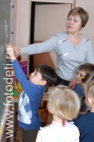 Дети с педагогом выполняют задания у доски, фото из архива детского фотографа