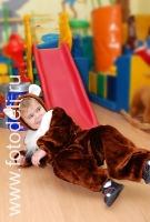 Ребенок в костюме медведя катается с горки, фото сделано на детском празднике