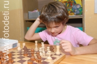 Мальчик обдумывает шахматный ход, на фото дети занимаются спортом