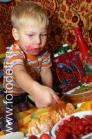 Малыш, лицо. которого вымазано клубникой, дети кушают самостоятельно