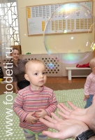 Ребёнок разглядывает большой мыльный пузырь, фото играющих малышей