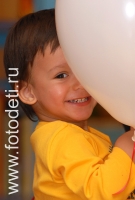 Ребёнок выглядывает из-за шарика, фото детей в фотобанке fotodeti.ru