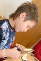 Мальчик аккуратно пользуется ножницами, на фотографии ребёнка из галереи «Детское творчество