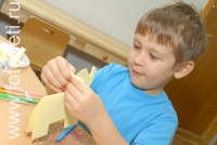 Мальчик вырезает фигурку  слонёнка из бумаги, на фотографии ребёнка из галереи «Детское творчество