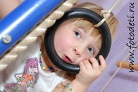 Девочка забавно выглядывает через спортивное кольцо, забавные фотографии детей на сайте детского фотографа