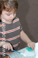 ребёнок наносит клей кисточкой, на фотографии ребёнка из галереи «Детское творчество