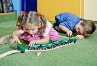 Дети строят игрушечную железную дорогу. Фотосъёмка детей в детских садах и в семье.