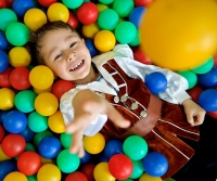 Ребёнок валяется на шариках, получая удовольствие. Фотограф уловил момент, чтобы сделать удачный кадр.
